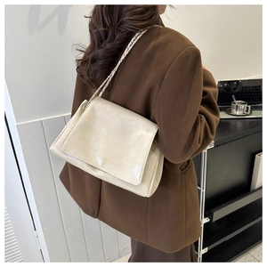 Détail du sac à bandoulière en cuir crème avec texture fine et bandoulière en chaîne dorée