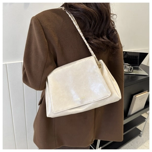 Sac bandoulière en cuir blanc crème avec bandoulière chaîne porté par un mannequin