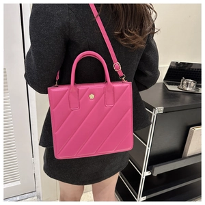 Detail of rose pink quilted tote bag with gold flower logo shown in an office setting