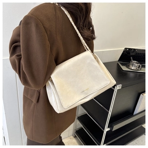 Détail du sac à bandoulière en cuir crème avec logo doré et sangle en chaîne tissée