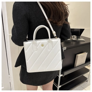 White quilted crossbody bag featuring a golden flower clasp and leather texture details