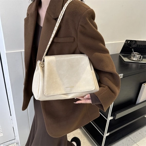 Sac cabas chic en cuir crème avec bandoulière chaîne sur un mannequin en manteau de laine