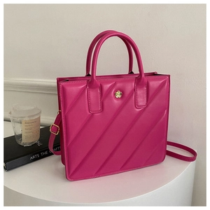Macro detail of magenta quilted tote bag with golden flower logo on a white pedestal