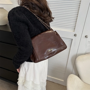 Sac cabas rétro marron foncé en cuir brillant avec bandoulière chaîne sur modèle