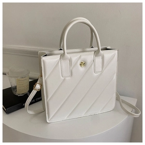 Detailed view of white quilted tote bag with golden rose clasp and elegant stitching