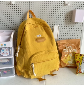 Detail view of yellow corduroy backpack featuring a cute 3D duck design and side water bottle pocket