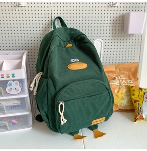 Close-up of a dark green corduroy backpack featuring a cute cartoon duck design