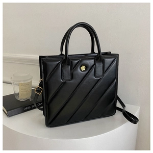 Close-up of black quilted tote bag featuring a golden flower clasp and dual handles