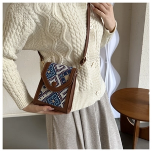 Détail d'un sac à bandoulière vintage tissé géométrique porté avec un pull beige