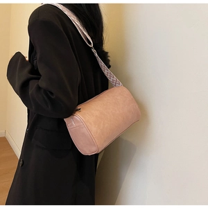 Détail du sac cylindrique rose avec large bandoulière à motifs géométriques porté par un mannequin