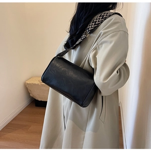 Détail du sac bandoulière cylindrique en cuir PU noir avec sangle tissée géométrique à l'épaule