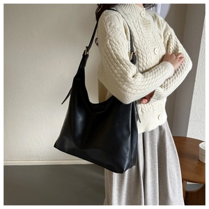 Detailed close-up of high-quality matte black hobo bag with elegant gold metal buckle