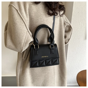 Close-up of black quilted small square bag featuring matte finish and gold metal branding