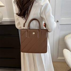 Minimalist brown quilted leather tote bag for commuting with gold floral logo and strap