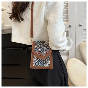 Détail d'un petit sac bandoulière bohème avec motifs géométriques et bordure en cuir marron