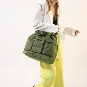 Army green nylon crossbody bag with three pockets and wide strap on model in studio