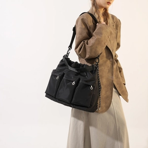 Minimalist large black nylon tote bag with three front pockets and wide shoulder strap