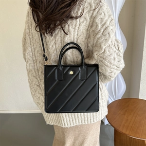 Minimalist black square handbag with diagonal stripe embossing and golden floral logo