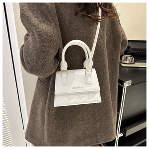 Close-up of white quilted leather mini crossbody bag with gold hardware and top handle