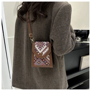 Détail d'un sac bandoulière vintage avec motifs tissés ethniques et bordures en cuir brun
