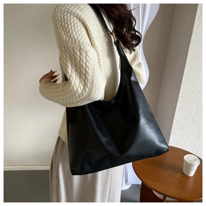 Modern black PU leather tote bag shown on model with adjustable strap and crescent shape