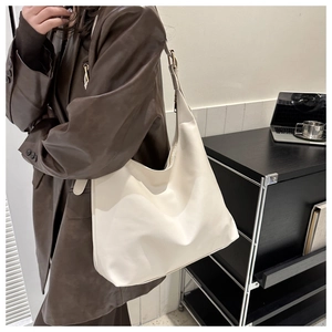 Fashionable oversized cream hobo bag shown with a leather blazer in a modern office setting