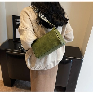 Sac bandoulière vert avec sangle tissée géométrique porté par un mannequin en décor