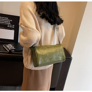 Détail du sac cylindre en cuir huilé vert avec bandoulière large à motifs tendance
