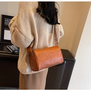 Détail du sac cylindre marron avec texture grainée et bandoulière aux motifs géométriques