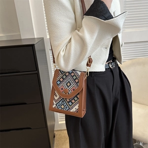 Petit sac bandoulière ethnique géométrique avec bordure en cuir marron porté par mannequin