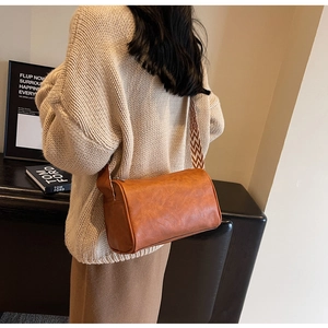 Gros plan du sac cylindrique marron avec bandoulière à motifs sur un mannequin