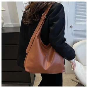 Brown leather Hobo bag shown on model highlighting the natural lychee texture and silver buckle