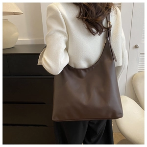 Detail of dark brown leather hobo bag showing adjustable shoulder strap with gold buckle