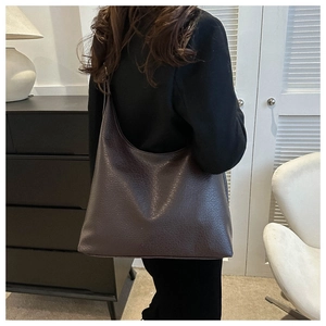 Detail of a large dark brown hobo bag showing pebbled leather texture and minimalist style