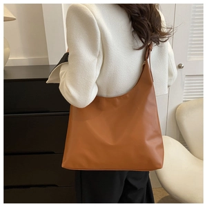 Rear view of a model wearing a brown minimalist hobo bag with adjustable strap