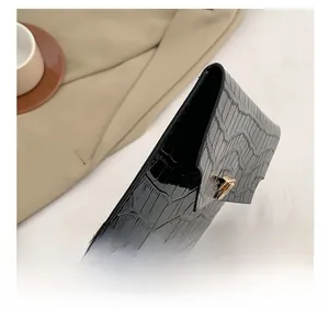 Detail view of black crocodile pattern envelope clutch bag with gold buckle side profile