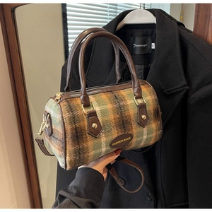 Détail du sac Boston à carreaux verts et marron avec poignées en cuir et fermetures dorées