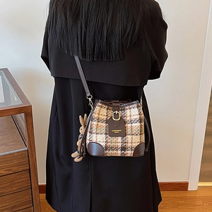 Plaid tweed bucket bag with dark brown leather trim and cute rabbit charm on black coat