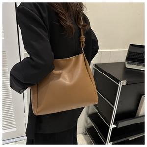 Détail du sac à bandoulière en cuir PU marron avec nœud décoratif et texture lisse