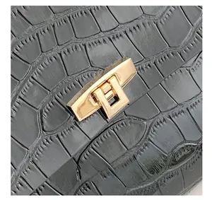 Detail shot of black crocodile embossed leather with a luxury gold metal twist lock