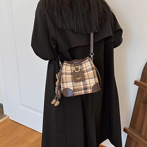 Retro plaid bucket bag with brown leather trim and cute plush rabbit charm on a model