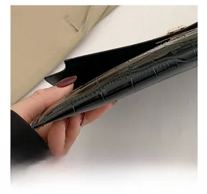 Close-up of black crocodile embossed leather texture and precise stitching on the envelope bag