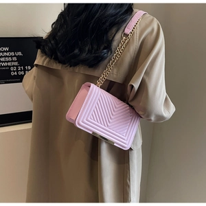 Detail of pink chevron quilted leather crossbody bag with gold chain and metal clasp