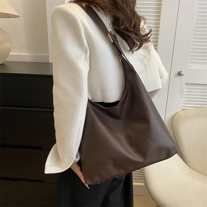 Minimalist deep brown leather crescent tote bag with adjustable wide strap on shoulder