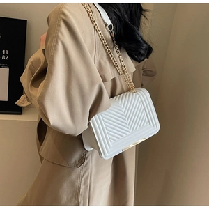 Close-up of a white chevron quilted square crossbody bag with gold chain strap