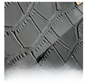Macro detail of black crocodile embossed leather texture with glossy finish and gold hardware