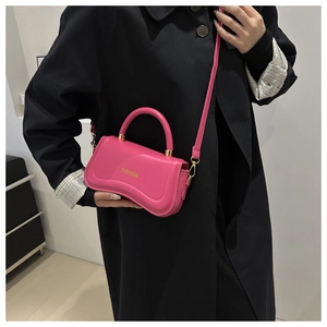 Détail du sac à bandoulière en cuir PU rose avec lettrage FASHION doré sur manteau noir