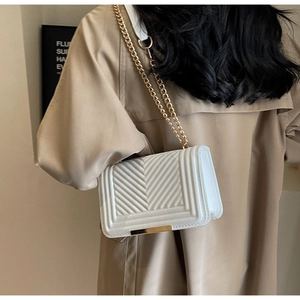 Detailed close-up of white quilted leather bag with elegant gold chain strap and metal trim
