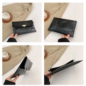 Detail view of black crocodile embossed envelope clutch bag with golden metal twist lock