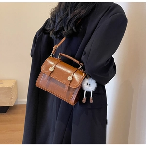 Detail view of brown vintage PU leather crossbody bag with a cute plush monster charm